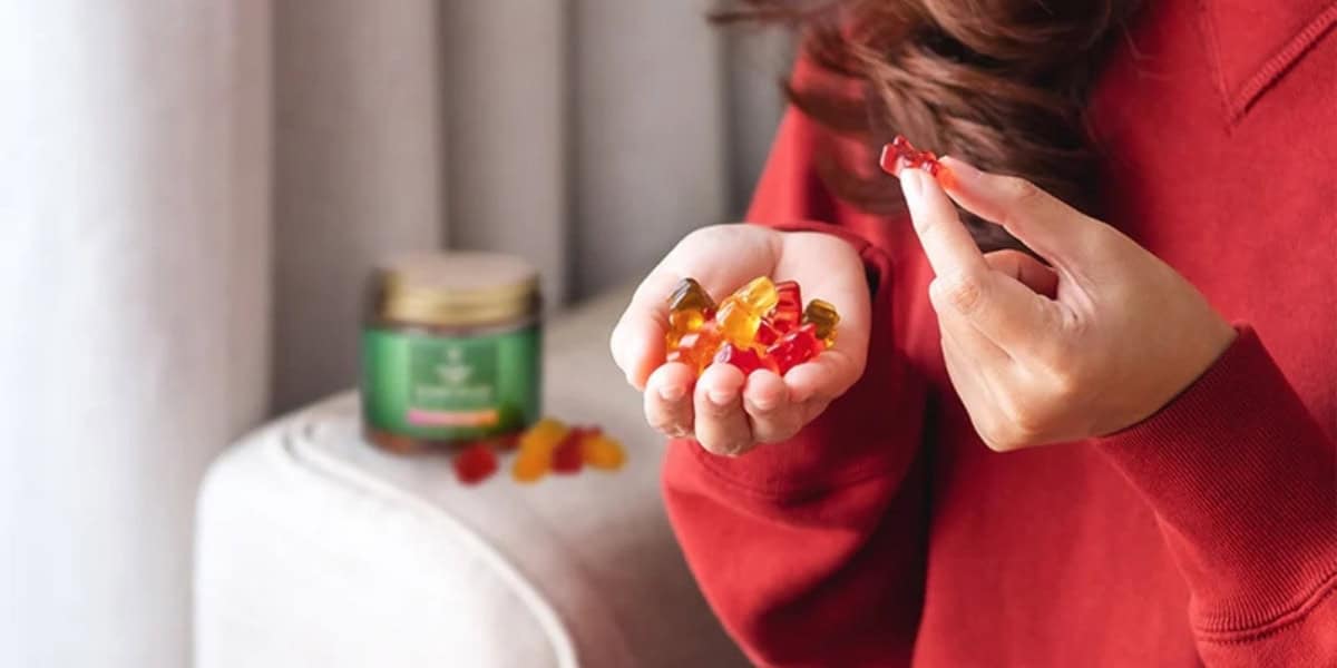 Woman eating CBD gummies with gummies on seatee blurred out background