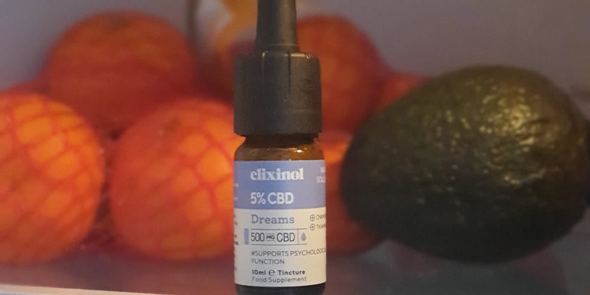 Bottle of CBD Oil stored in the fridge with oranges and avacados in the background