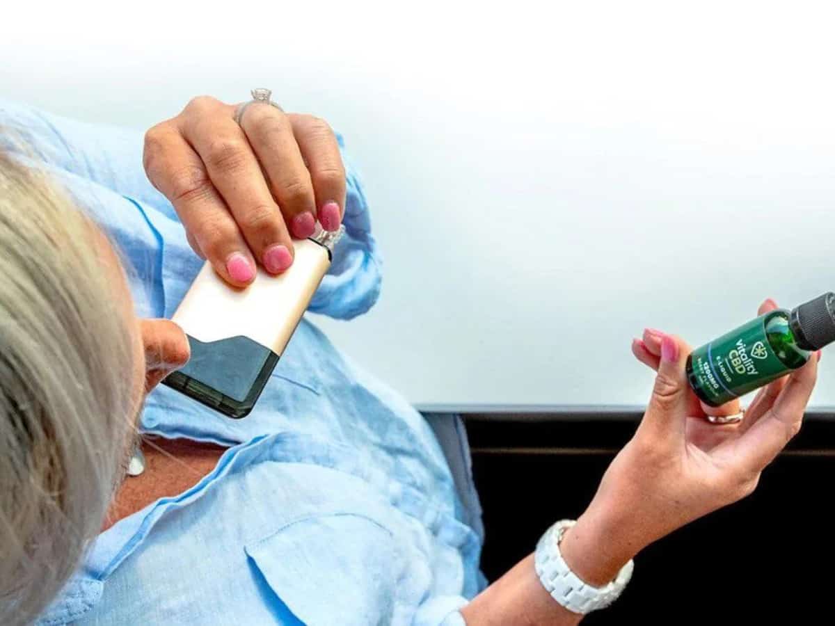 Girl vaping and holding Vitality CBD E-Liquid