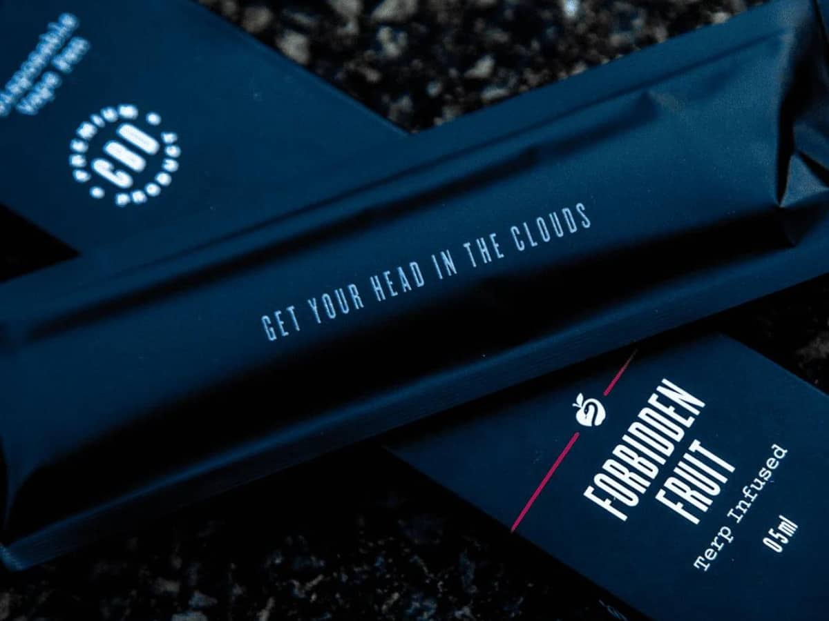 The Goods Forbidden Fruit flavoured CBD Disposable Vape Pen lying on gronud with "get your head in the clouds" written on the black packaging