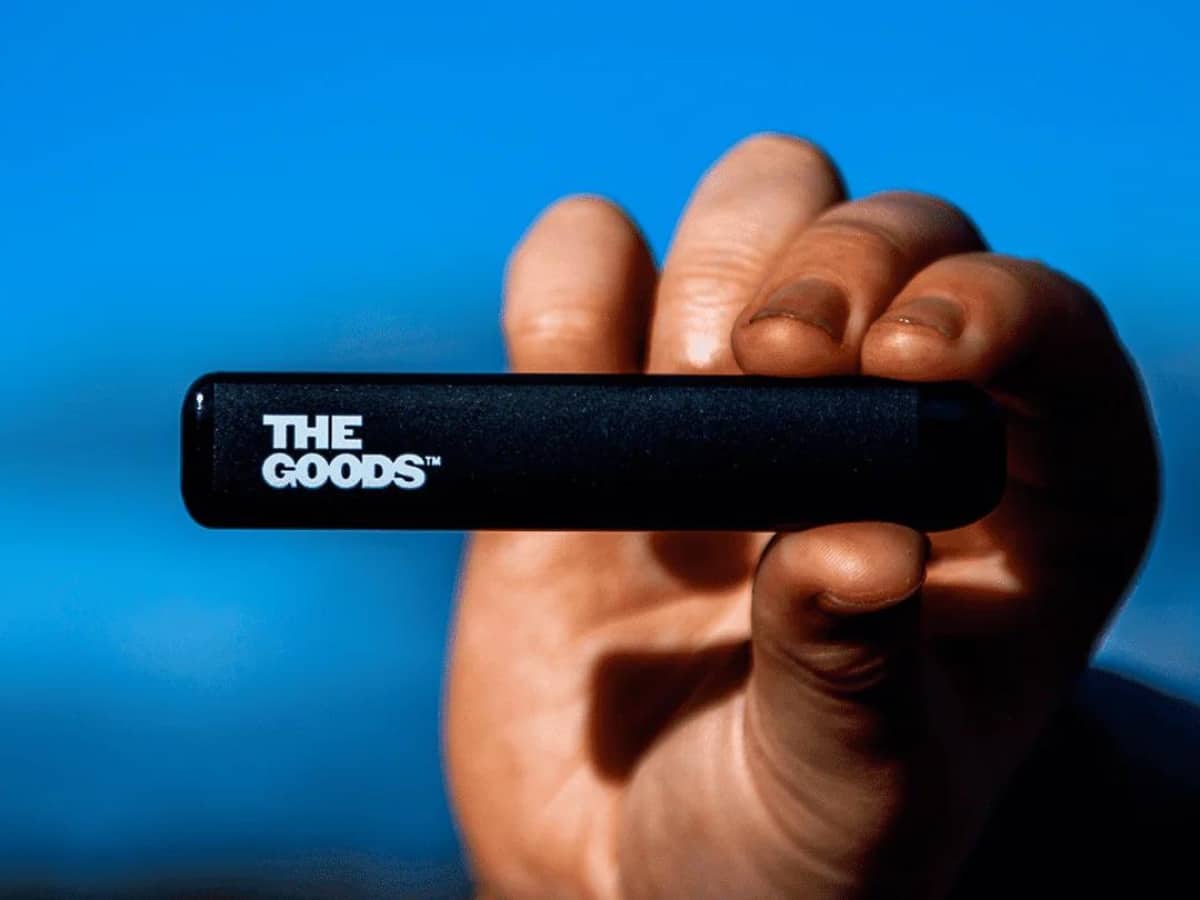 Man holding the Goods CBD Disposable Vape pen with blue sky backdrop