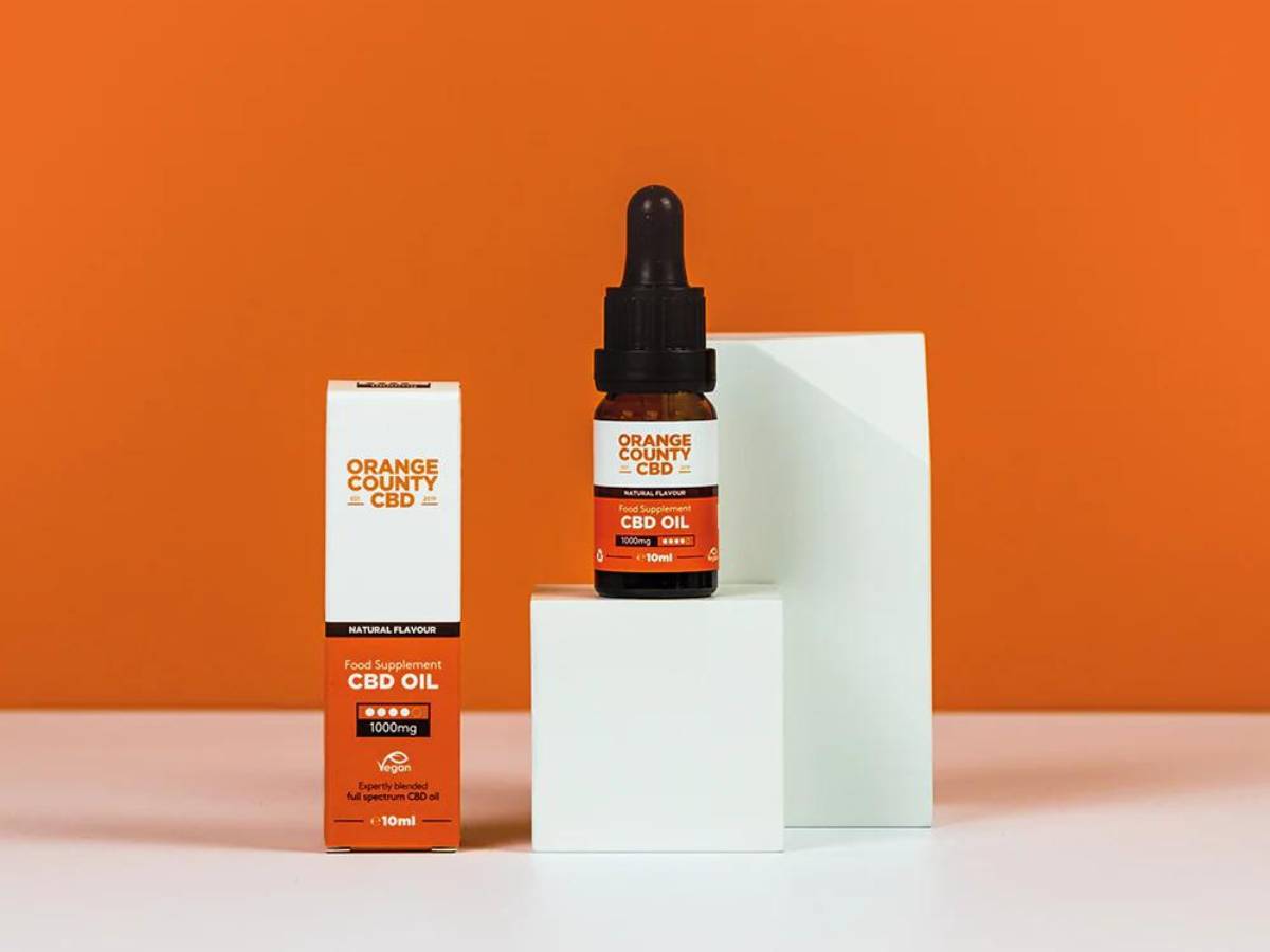 Orange County Full Spectrum CBD Oil 500mg box on podium beside bottle on white table with orange background