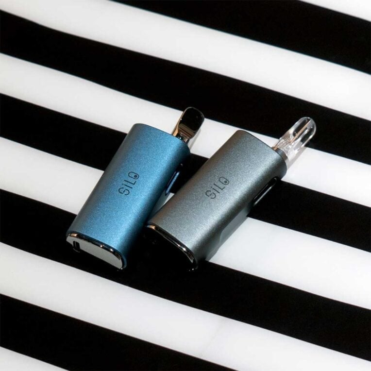 2x CCELL Silo Battery Black resting on striped background
