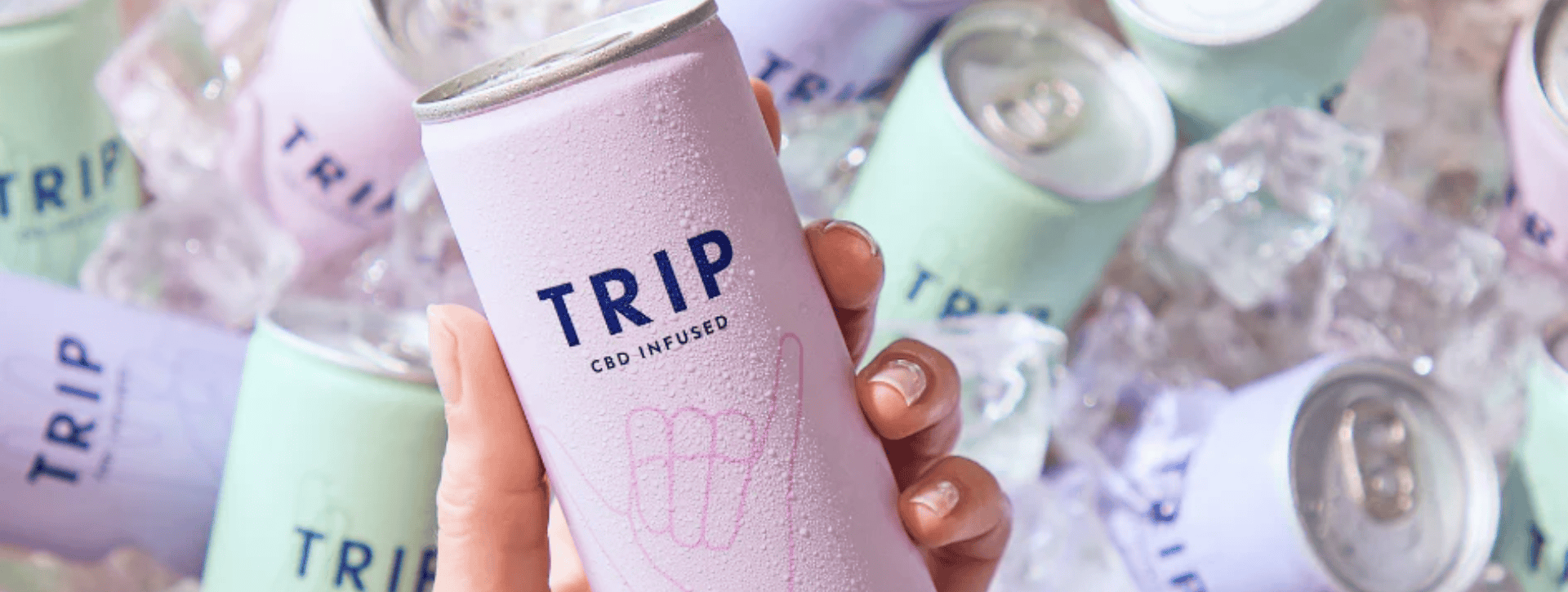 Hand holding TRIP CBD drink with multiple other drinks in an ice cooler behind