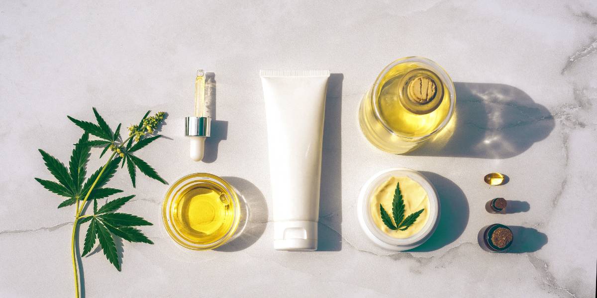 Various skin care and cosmetic products in a line, with hemp leaves