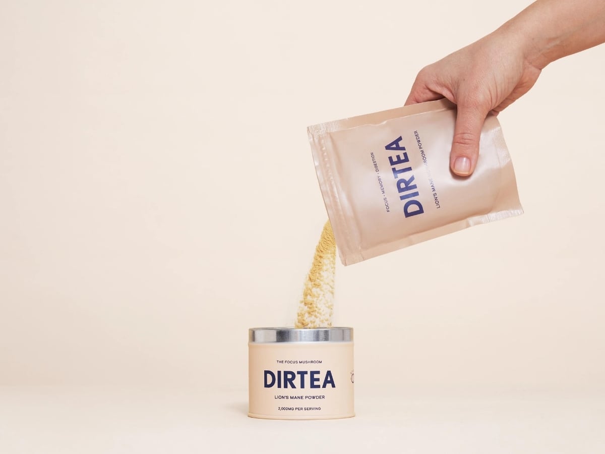 Pouring Dirtea Mushroom Powder refill into tin cream background