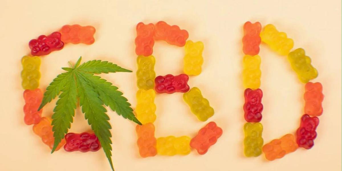 the term 'CBD' written out in cbd gummies with a hemp leaf on a cream background