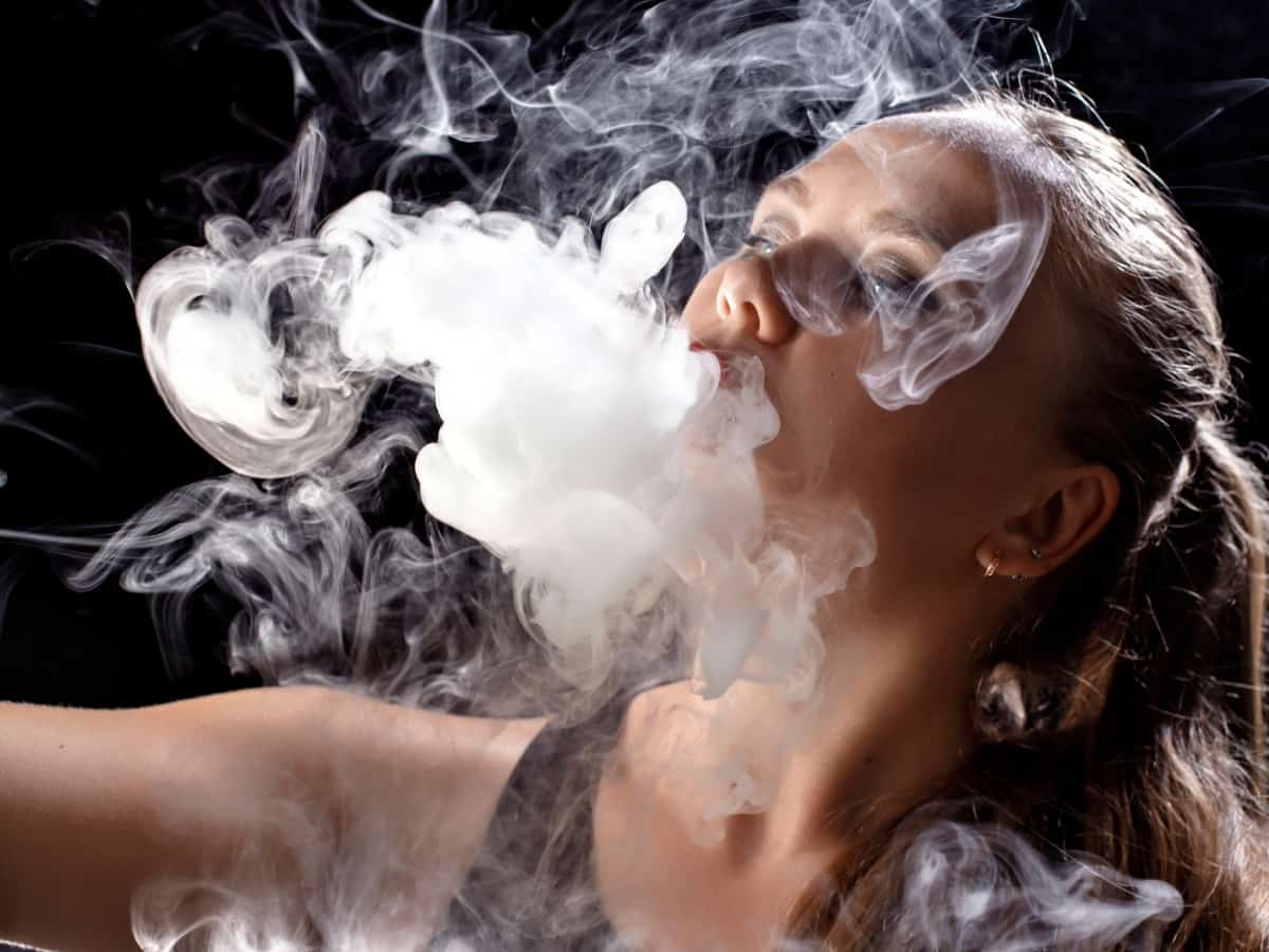 close-up of a woman blowing a cloud of smoke