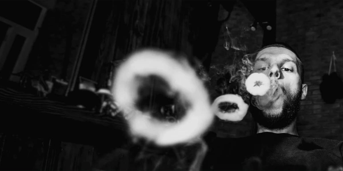 a man in black and white blowing smoke rings