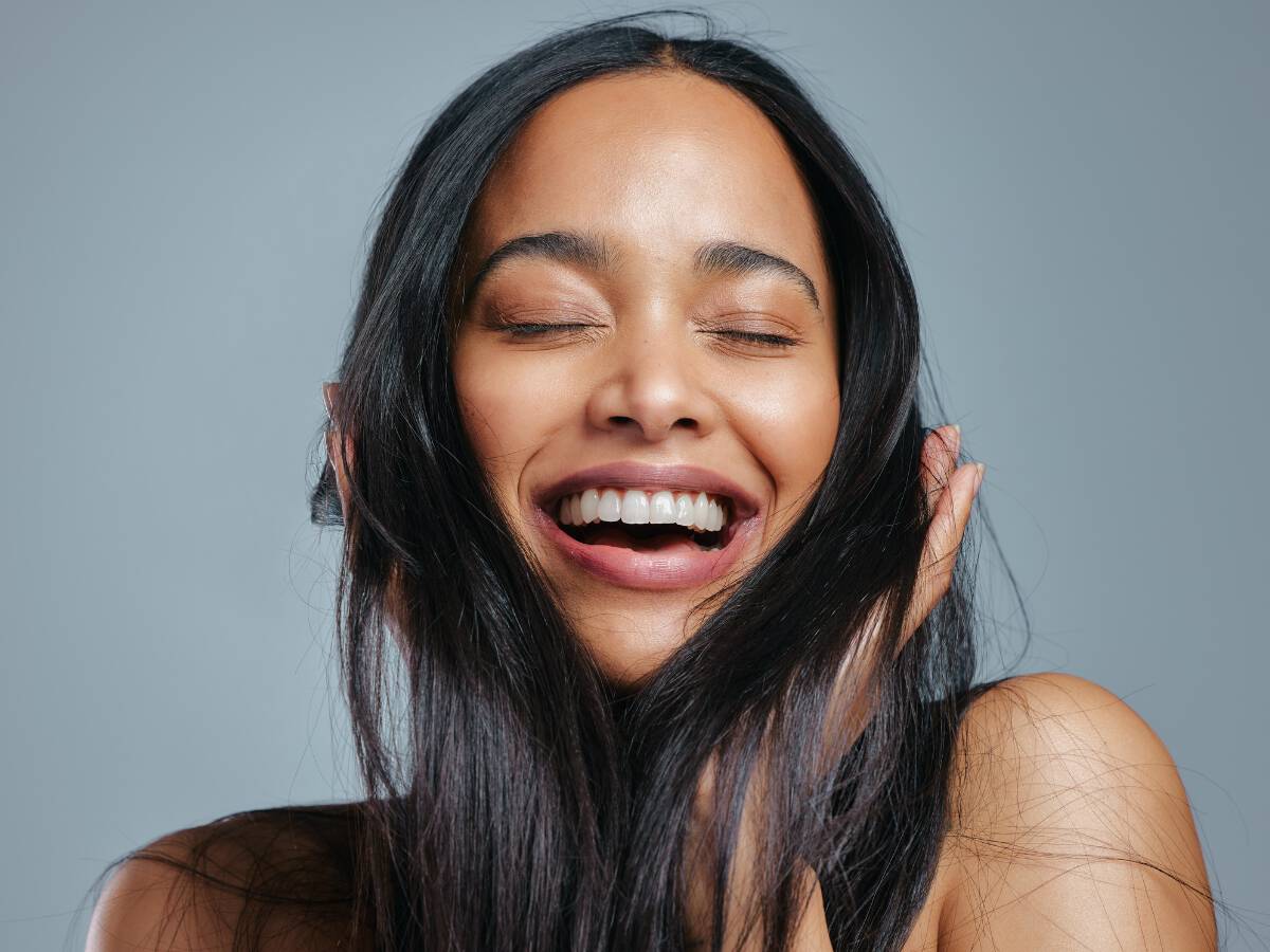 woman with dark hair and clear skin smiling