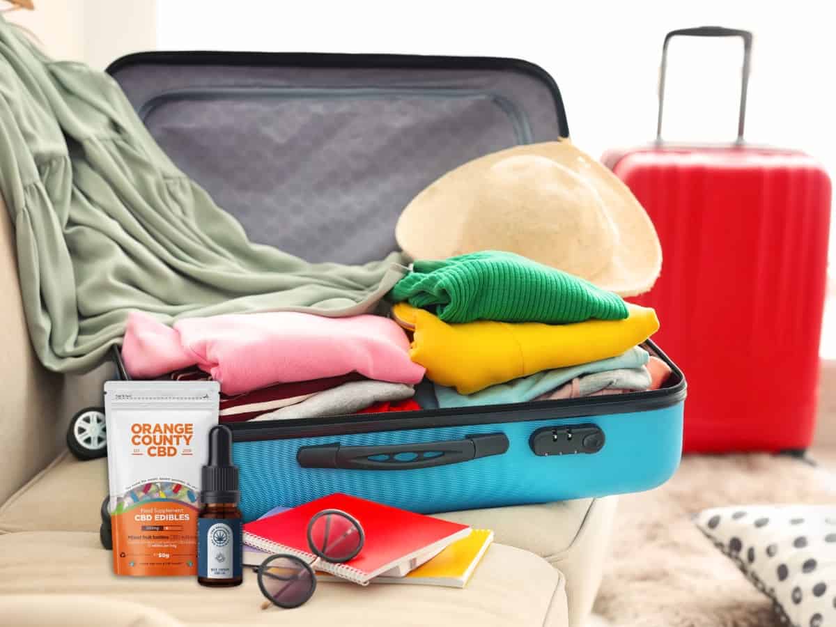 an open suitcase being packed, with a bottle of cbd brothers blue cbd oil and a orange county cbd grab bag ready to be packed for the trip