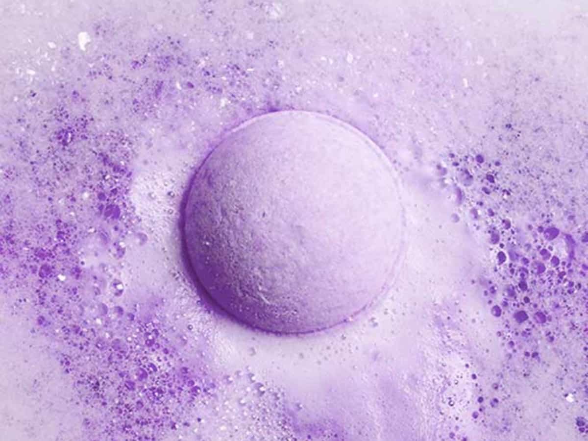 Vitality purple CBD bath bomb exploding in water