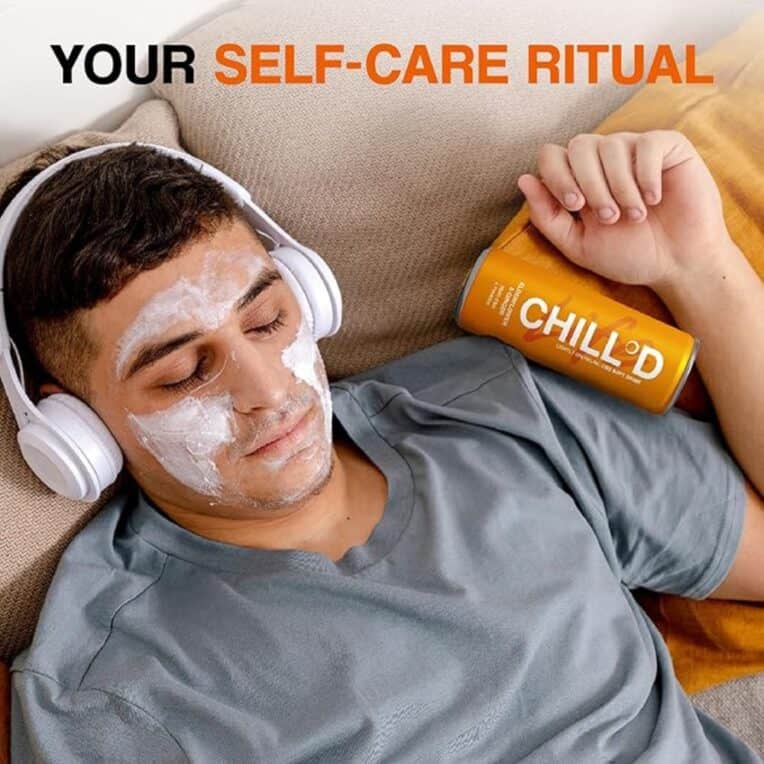 "Your self-care ritural" man with facemask, headphones lying on sofa with CHILL°D Elderflower Ginger