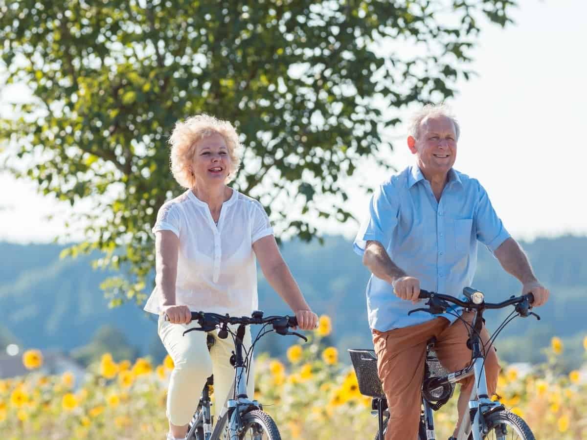 a man and a woman riding bikes through the countryside, happily benefiting from cbd 