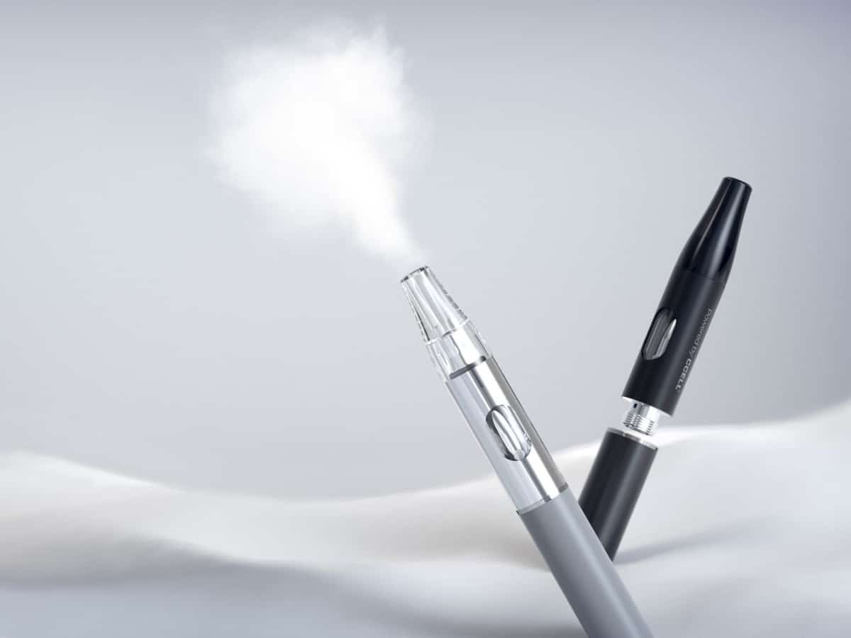 two ccell klean vape carts against a white background, with one expelling a cloud of vape smoke