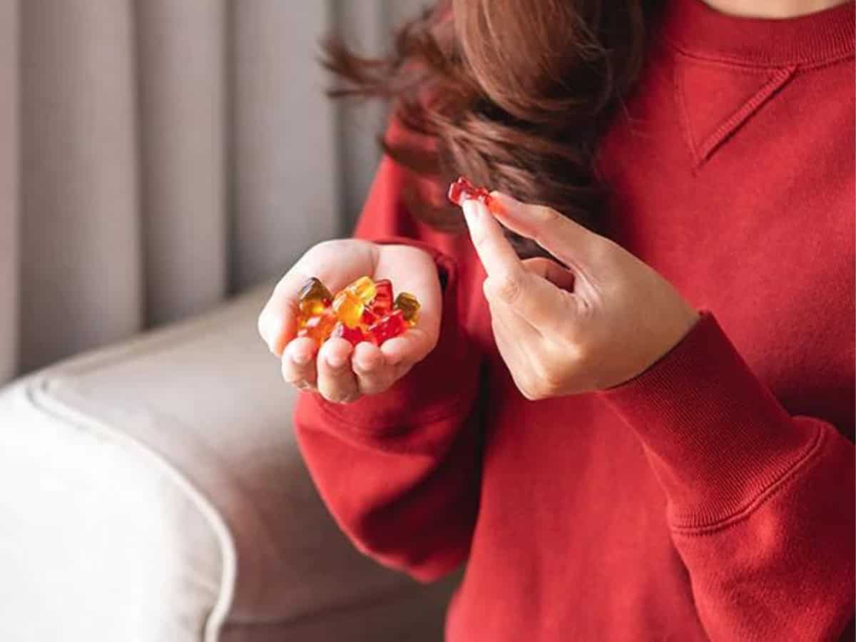 A woman in a red jumper with a handful of cbd gummies 