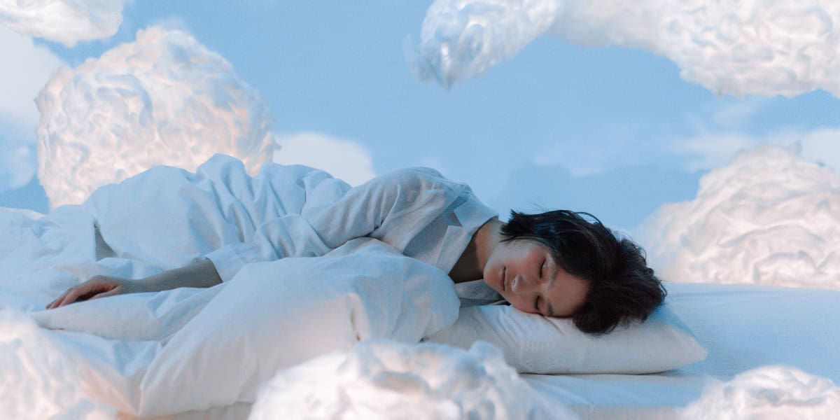 a woman resting in a white bed with a blue background surrounded by clouds