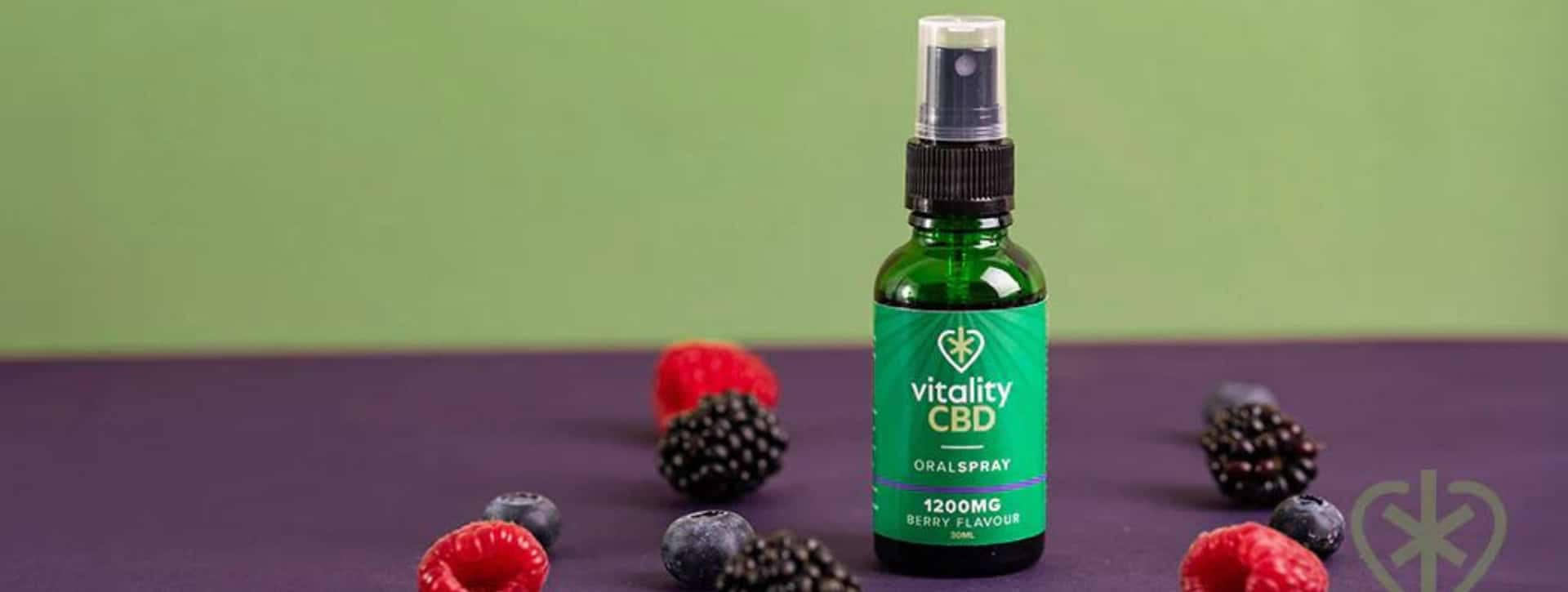 Vitality CBD Oil Isolate Oral Spray Berry Flavour surrounded by mixed berries with purple and green background