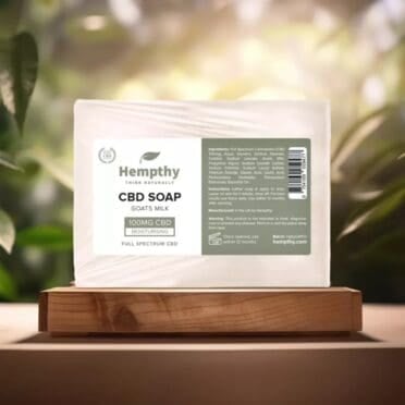 Hempthy CBD Soap Goats Milk on wooden table with forest light breaking through trees background