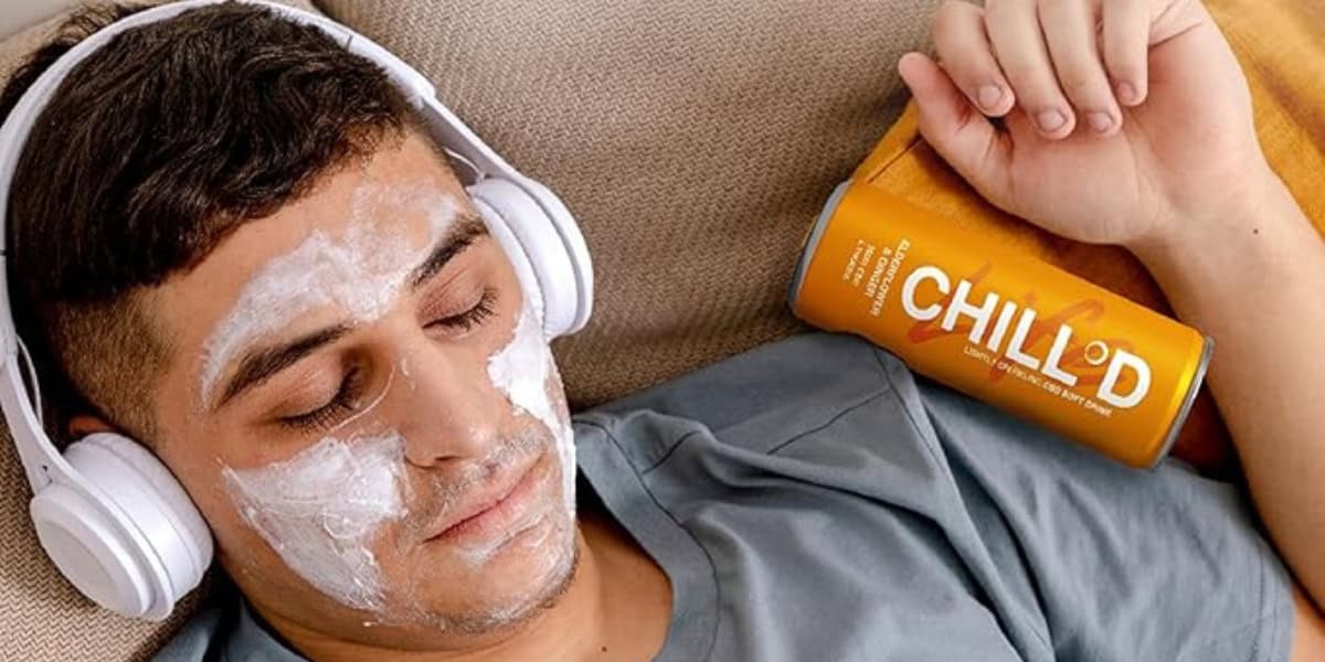 Man listening to music relaxing with his eyes closed and a face mask on his skin with a can of Chilld CBD drink beside him